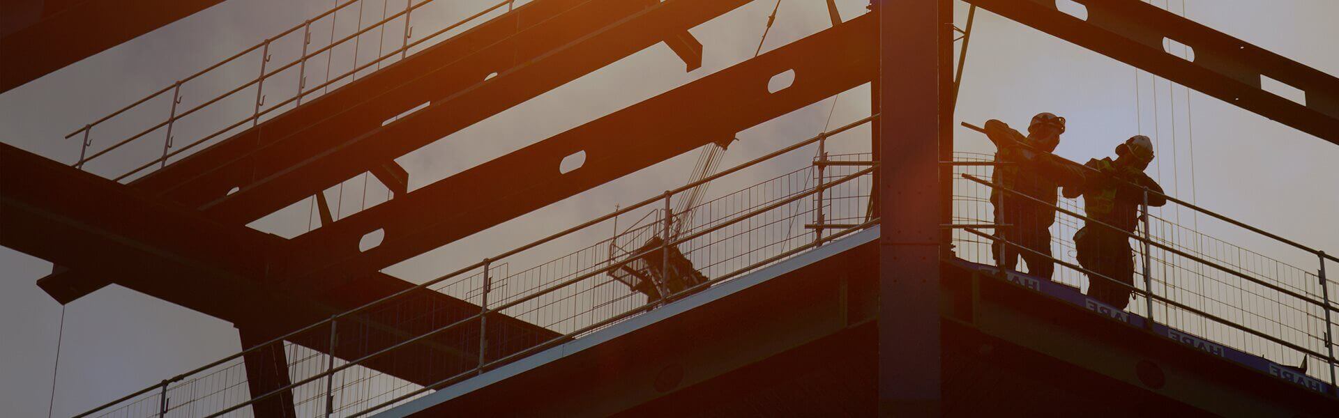 Image of to two silhouetted construction workers stood on scaffolding